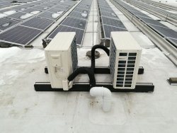 Projekt: Klimatisierung von zwei Serverräumen<br>Foto: Klima-Außeneinheit auf Montagekonsolen mit Verrohrung im Schutzschlauch auf dem Dach